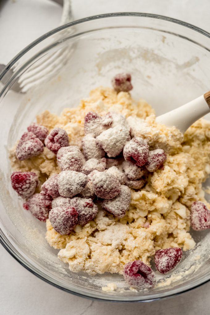 Raspberry white chocolate chip scone dough coming together in a bowl with a large spatula.