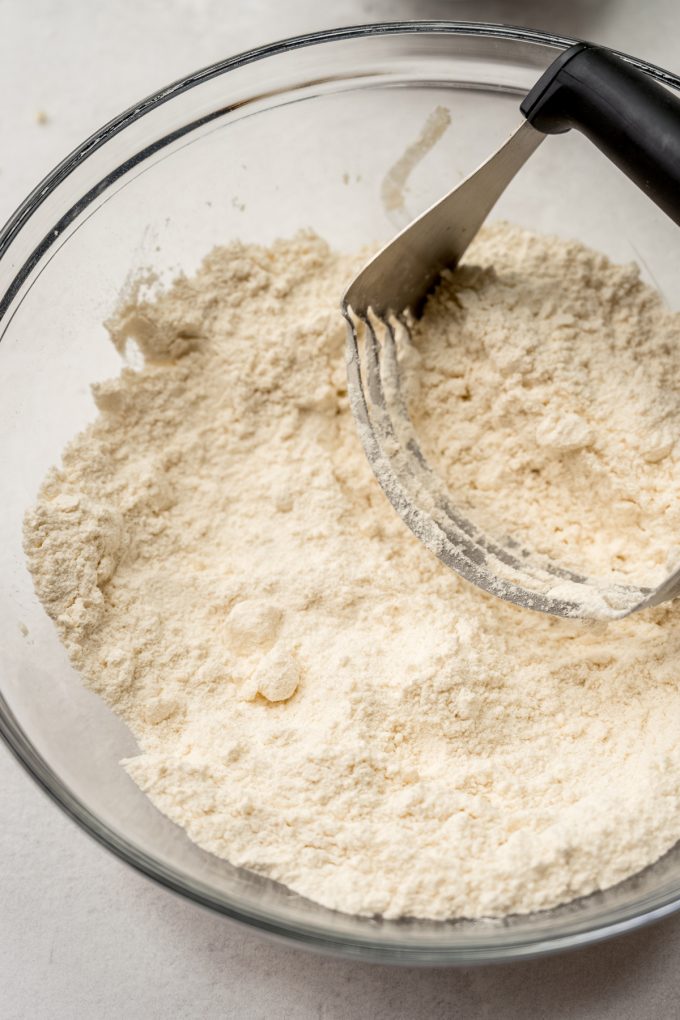The dough for scones in a bowl with a pastry cutter sitting in it.