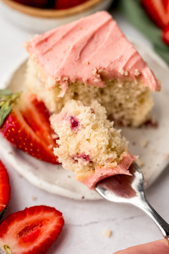 A slice of strawberry sheet cake on a plate with a fork.
