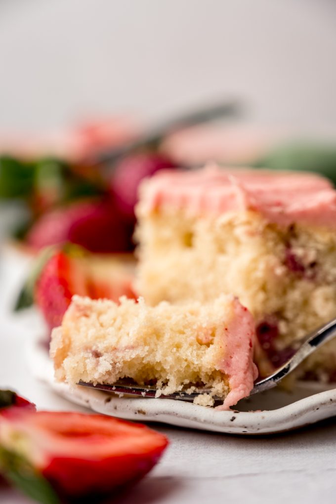 A slice of strawberry sheet cake on a plate with a fork.