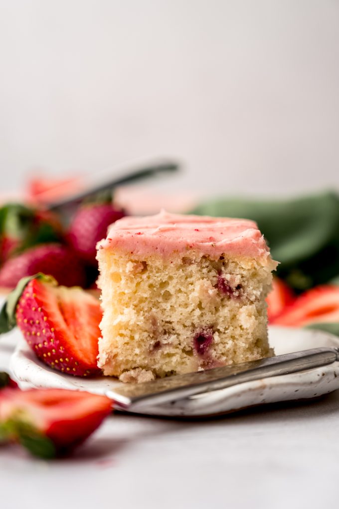 A slice of strawberry sheet cake on a plate with a fork.