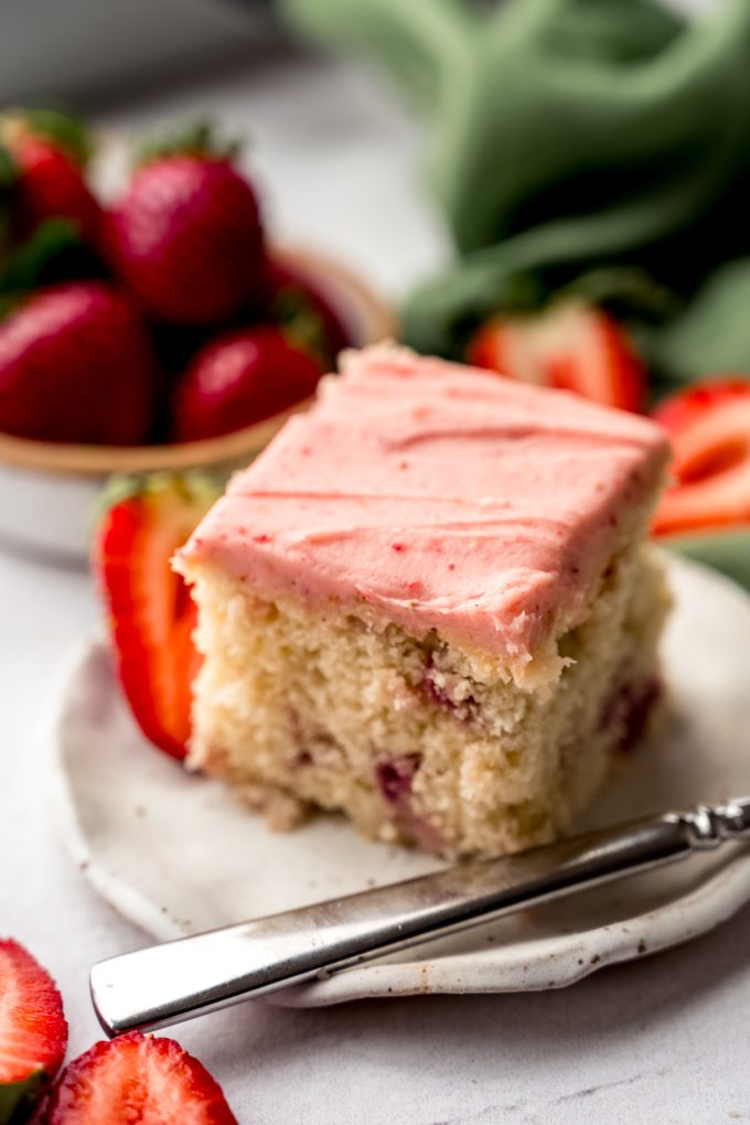 A slice of strawberry sheet cake on a plate with a fork.