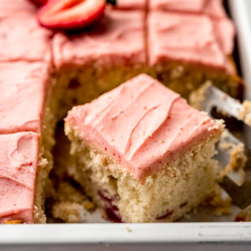 Sliced strawberry sheet cake in a pan.