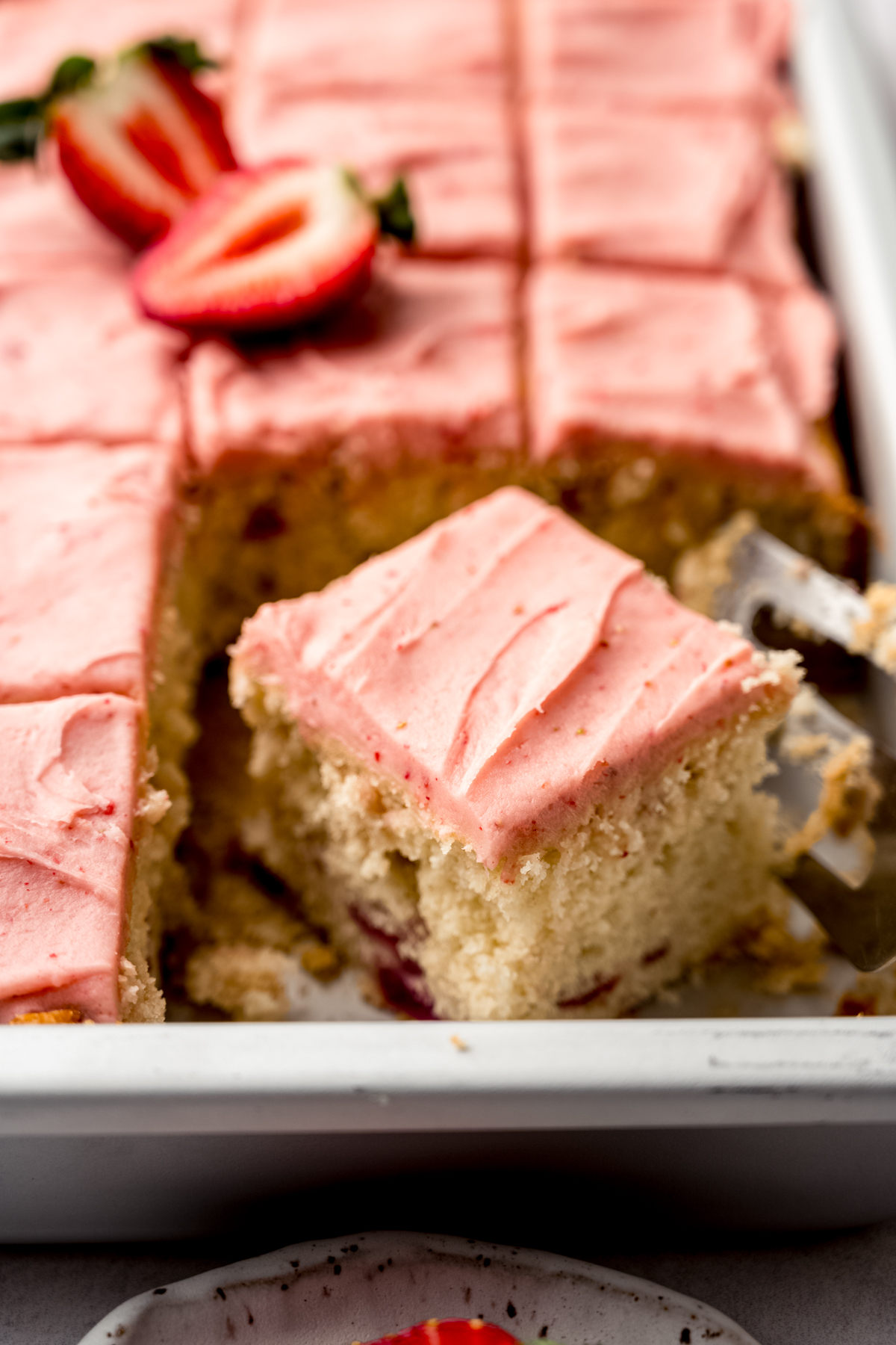 Sliced strawberry sheet cake in a pan.