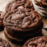 A stack of dark chocolate cookies on a surface.