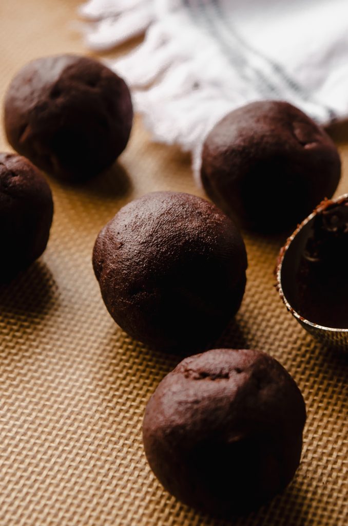 Dark chocolate cookie dough balls on a baking sheet.