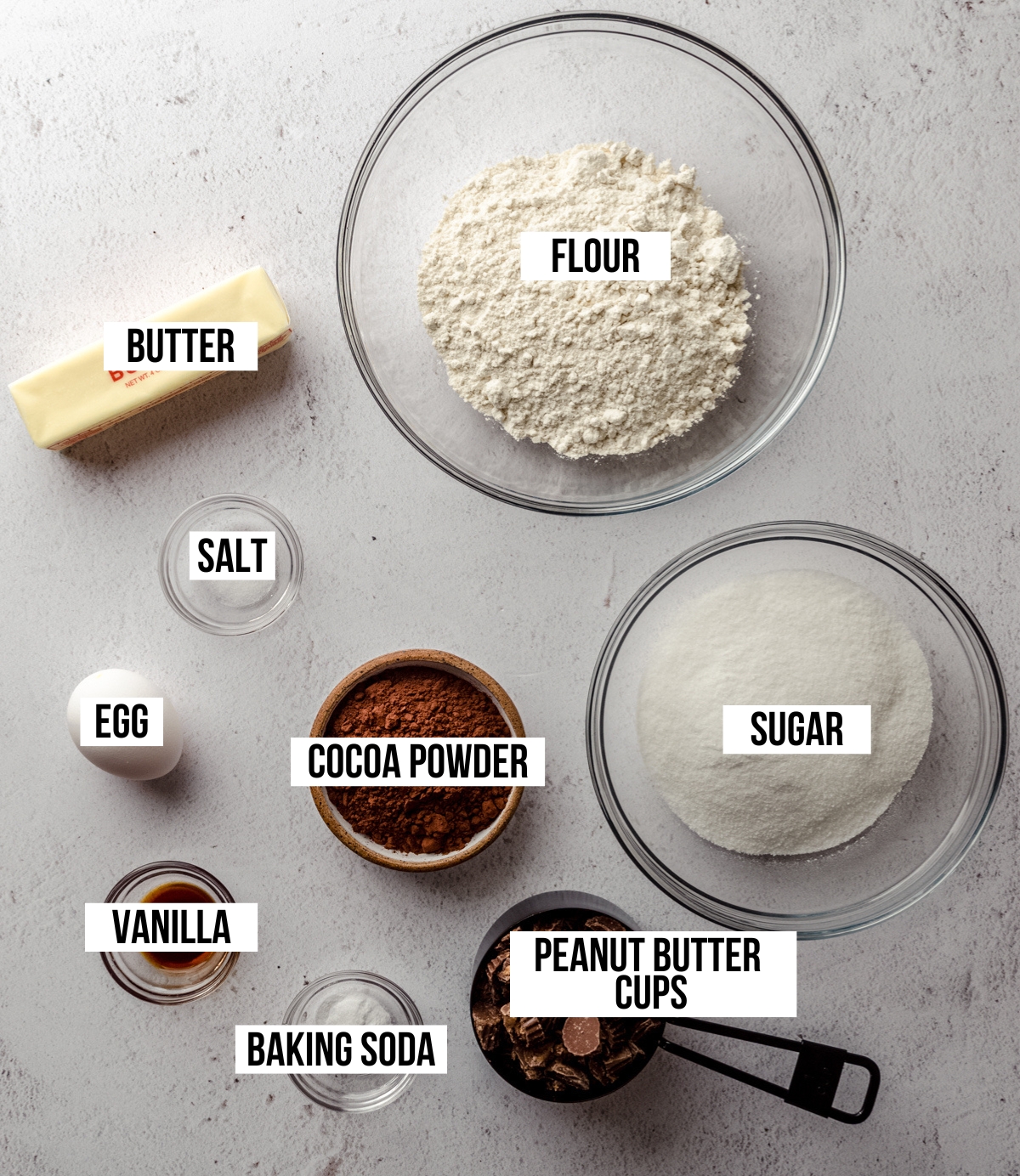 Aerial photo of ingredients to make chocolate peanut butter cup cookies with text overlay labeling each ingredient.