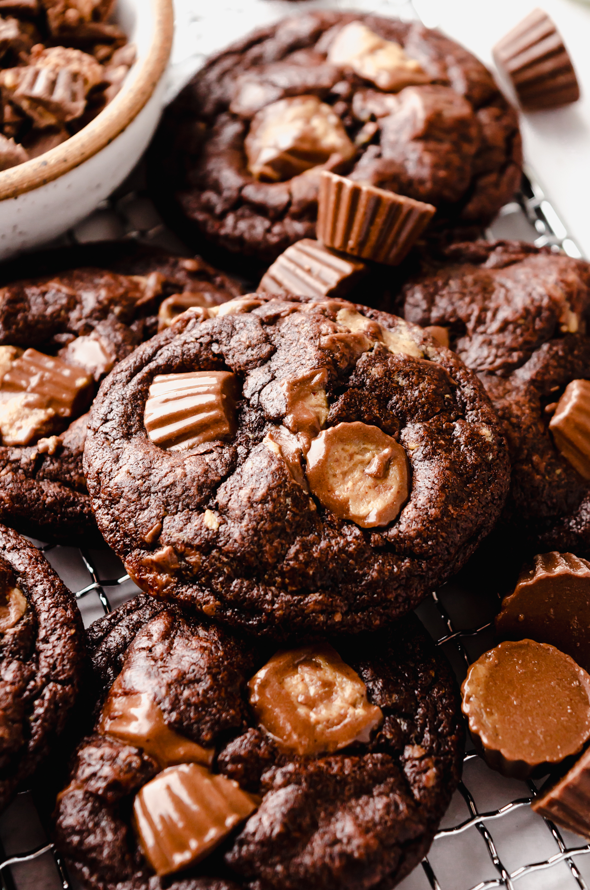 A photo of a chocolate peanut butter cup cookie on a surface with peanut butter cups around it.