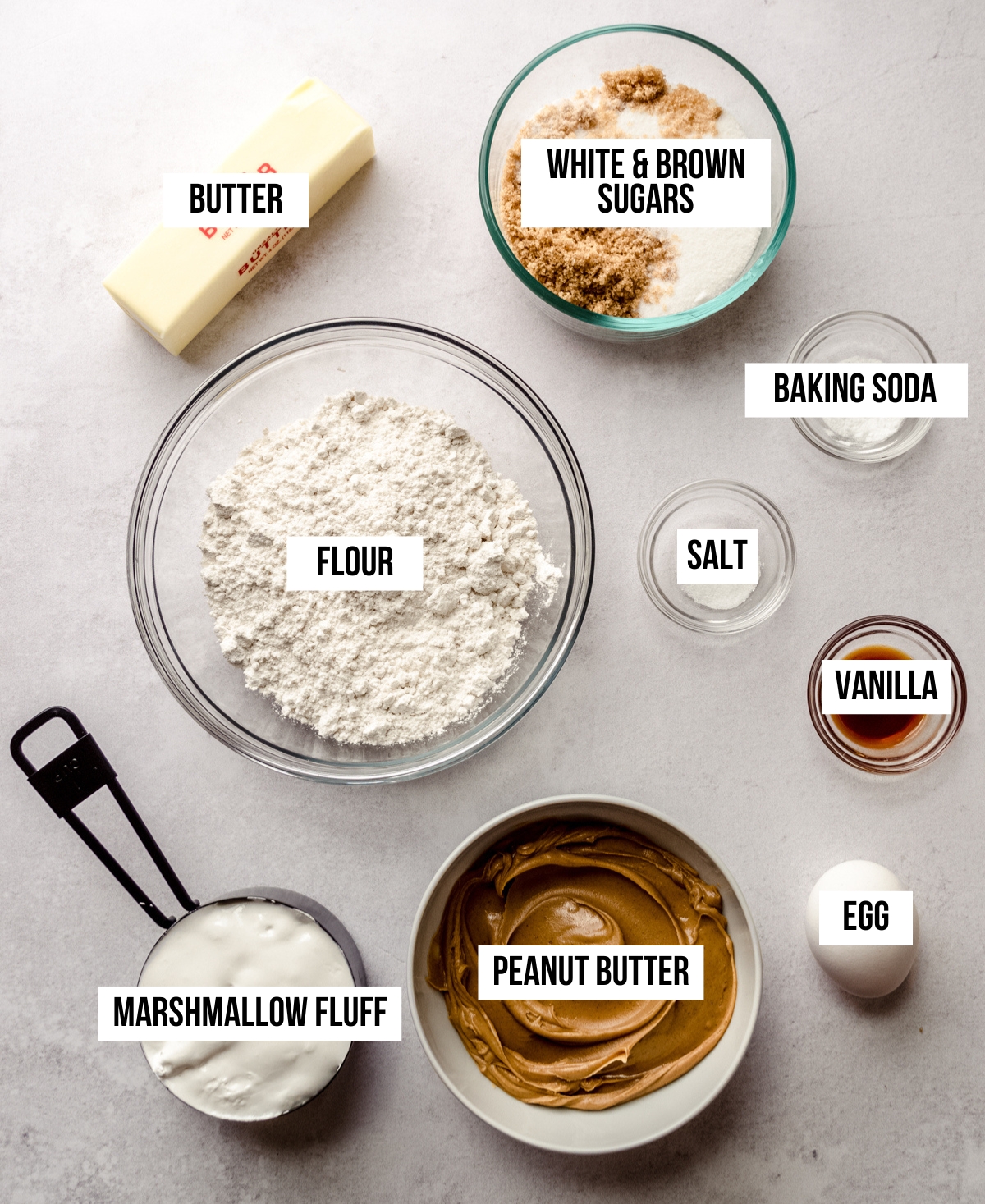 Aerial photo of the ingredients to make fluffernutter peanut butter cookies with text overlay labeling each ingredient.