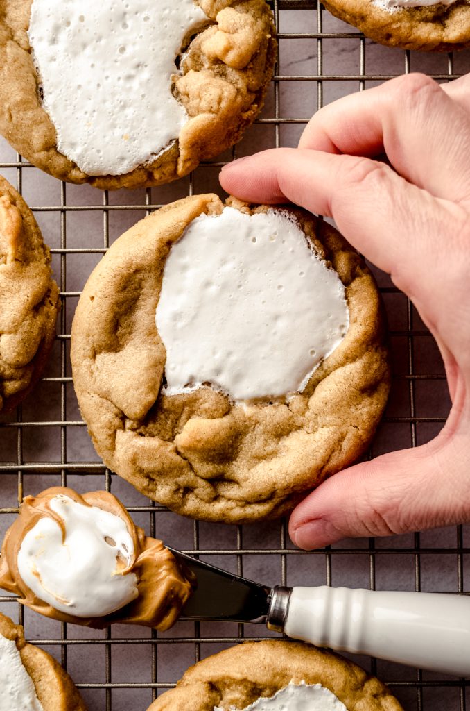 Someone is picking up a fluffernutter cookie from a cooling rack.