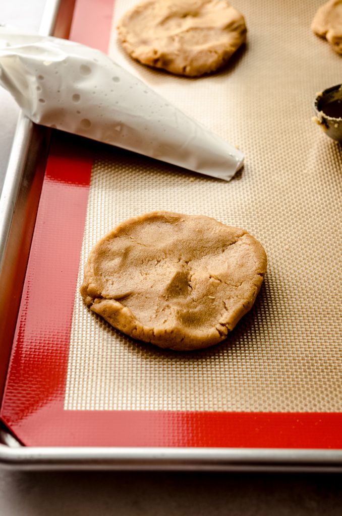 A disc of peanut butter cookie dough on a baking sheet.