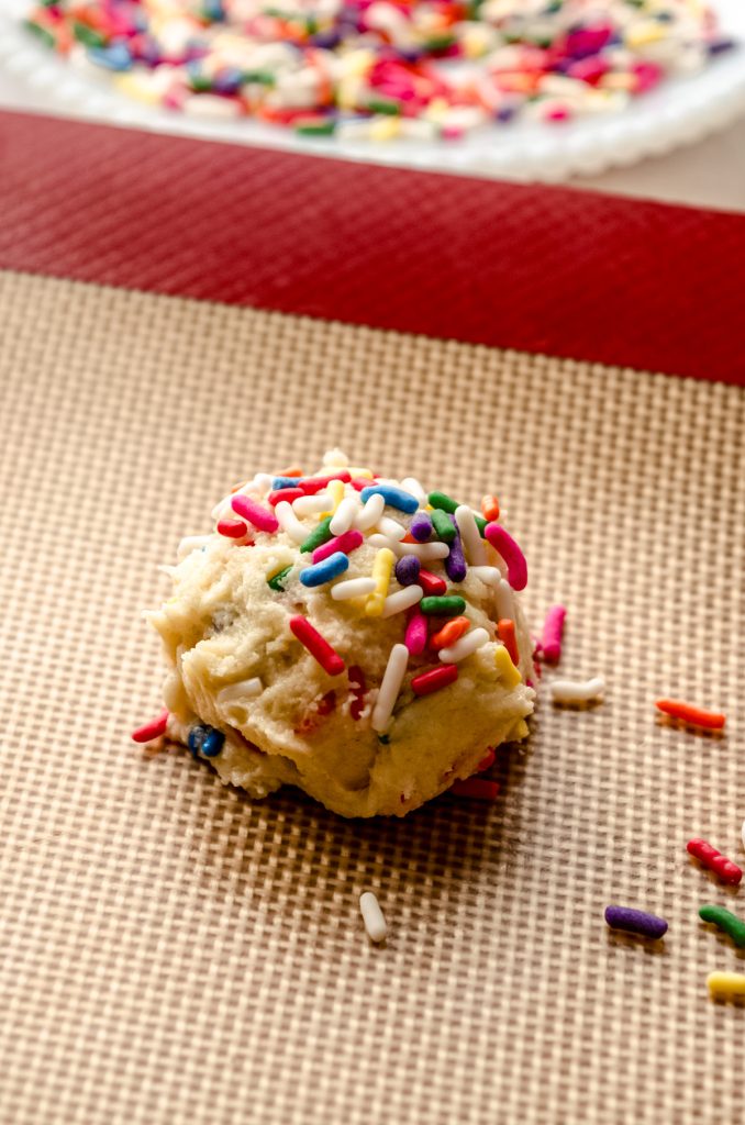 A ball of funfetti sugar cookie dough on a baking sheet.