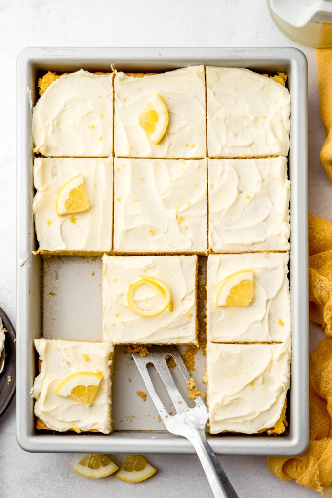 Aerial photo of a lemon sheet cake sliced and sitting in a baking pan.