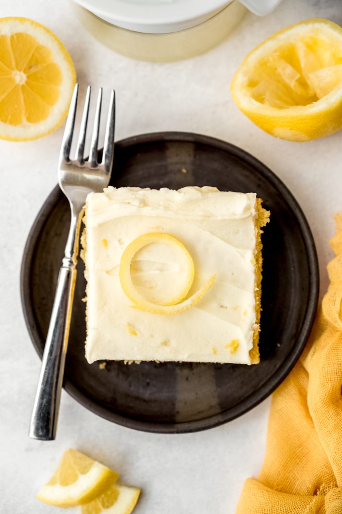 Aerial photo of a slice of lemon sheet cake on a plate with a fork.