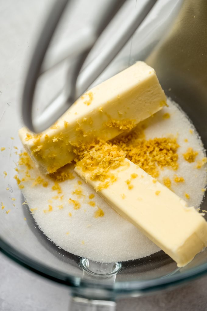 Sugar, butter, and lemon zest in a large glass mixing bowl.