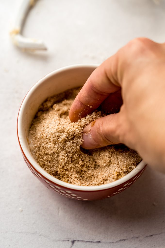 Someone is using their fingers to blend orange zest into the spiced filling for orange rolls.