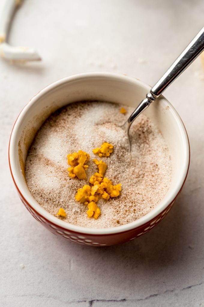 Orange zest in a bowl of cinnamon sugar filling to make orange cinnamon rolls.