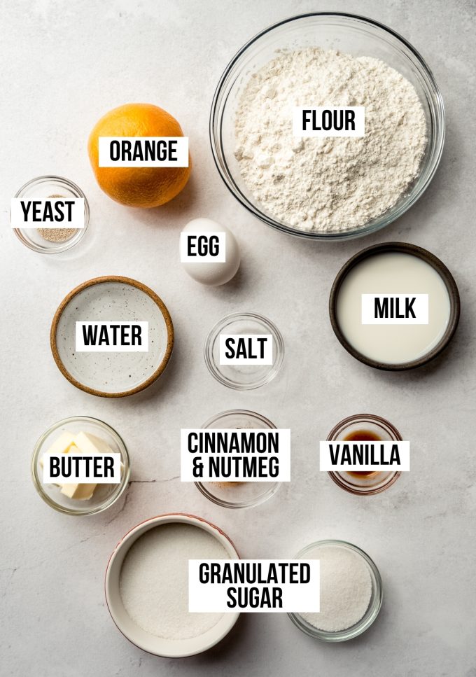 Aerial photo of ingredients to make orange cinnamon rolls with text overlay labeling each ingredient.