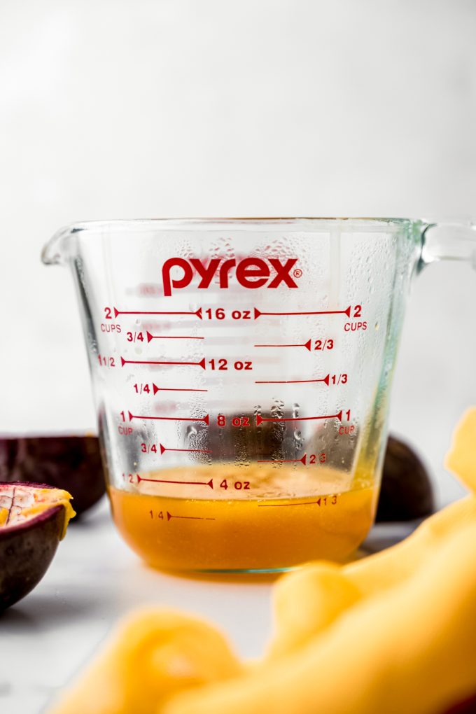 A glass measuring cup with passion fruit reduction in it.