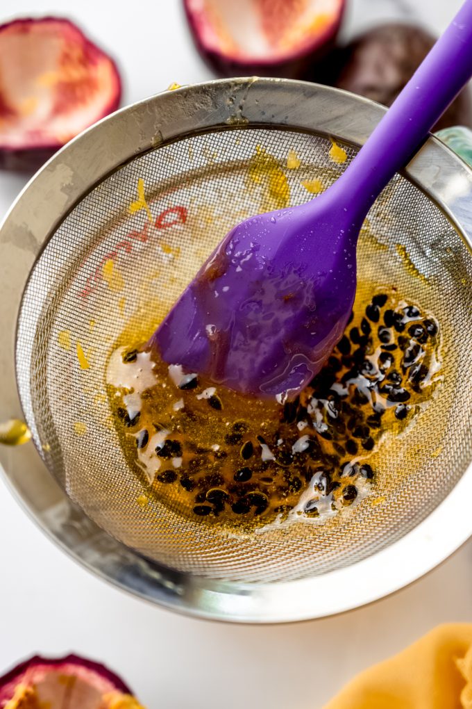 Someone is pressing passion fruit reduction through a sieve to separate the seeds.