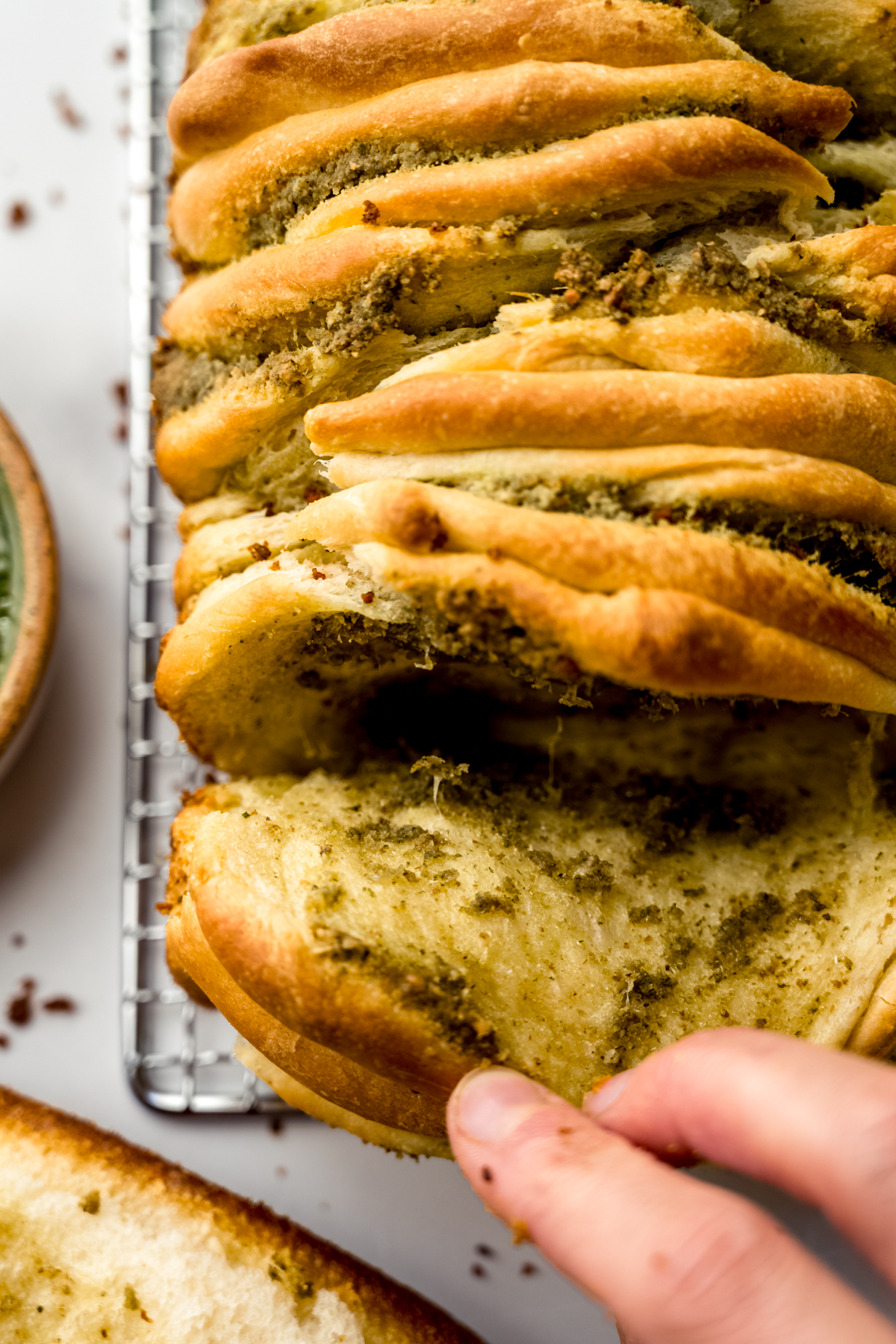 Aerial photo of pesto pull-apart bread that someone is pulling apart.