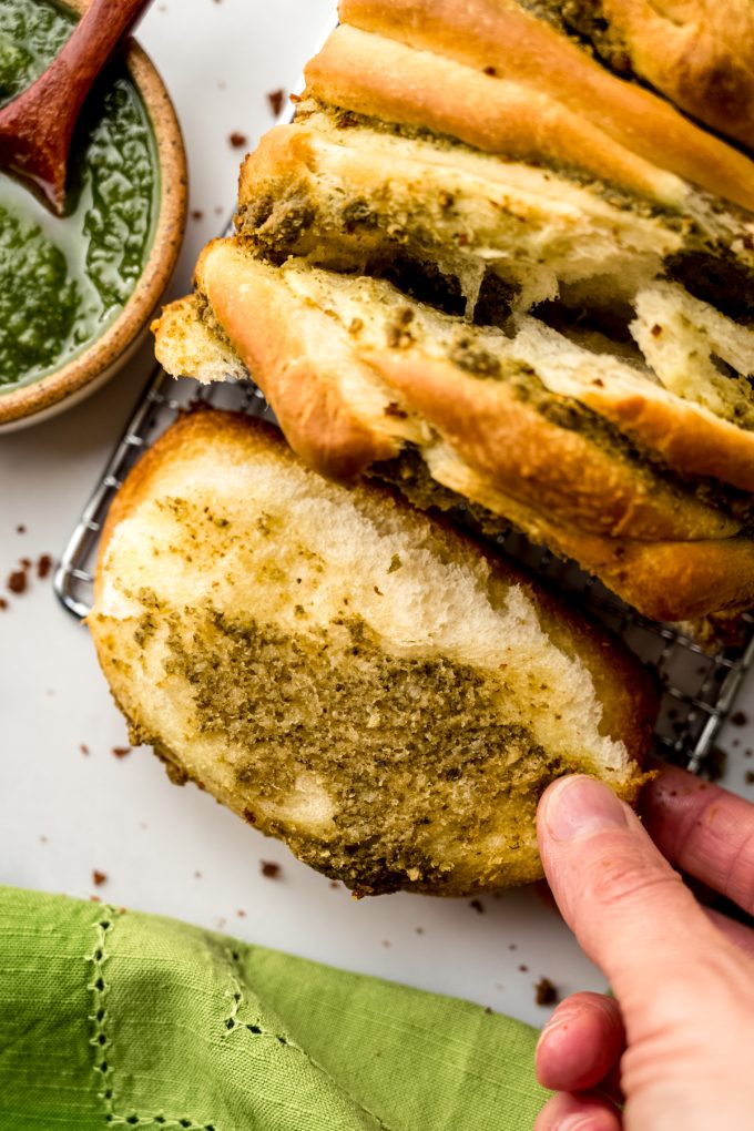 Aerial photo of pesto pull-apart bread that someone is pulling apart.