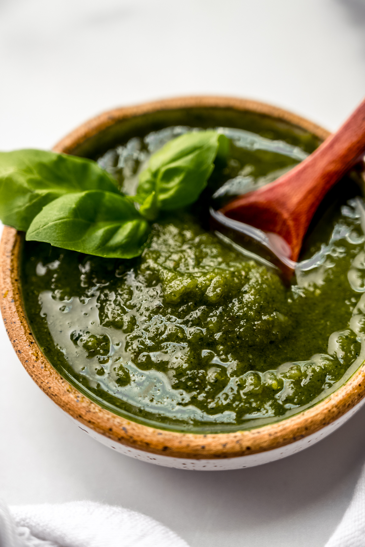 A bowl of homemade pesto with a small wooden spoon in it.