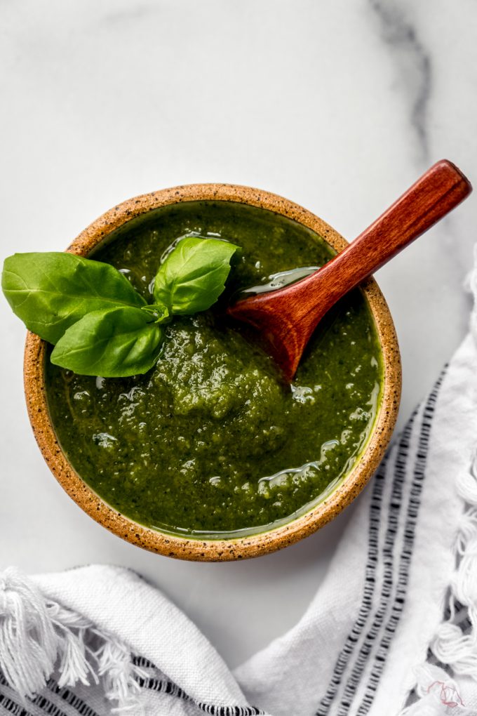A bowl of homemade pesto with a small wooden spoon in it.
