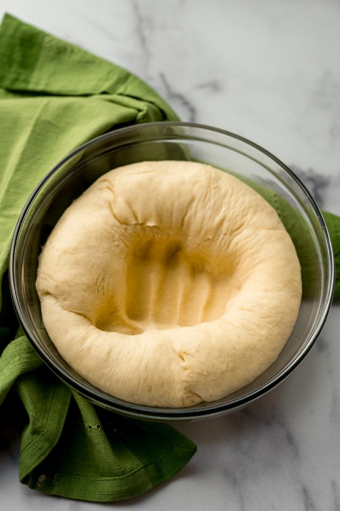 A loaf of yeasted dough in a bowl after being punched down.
