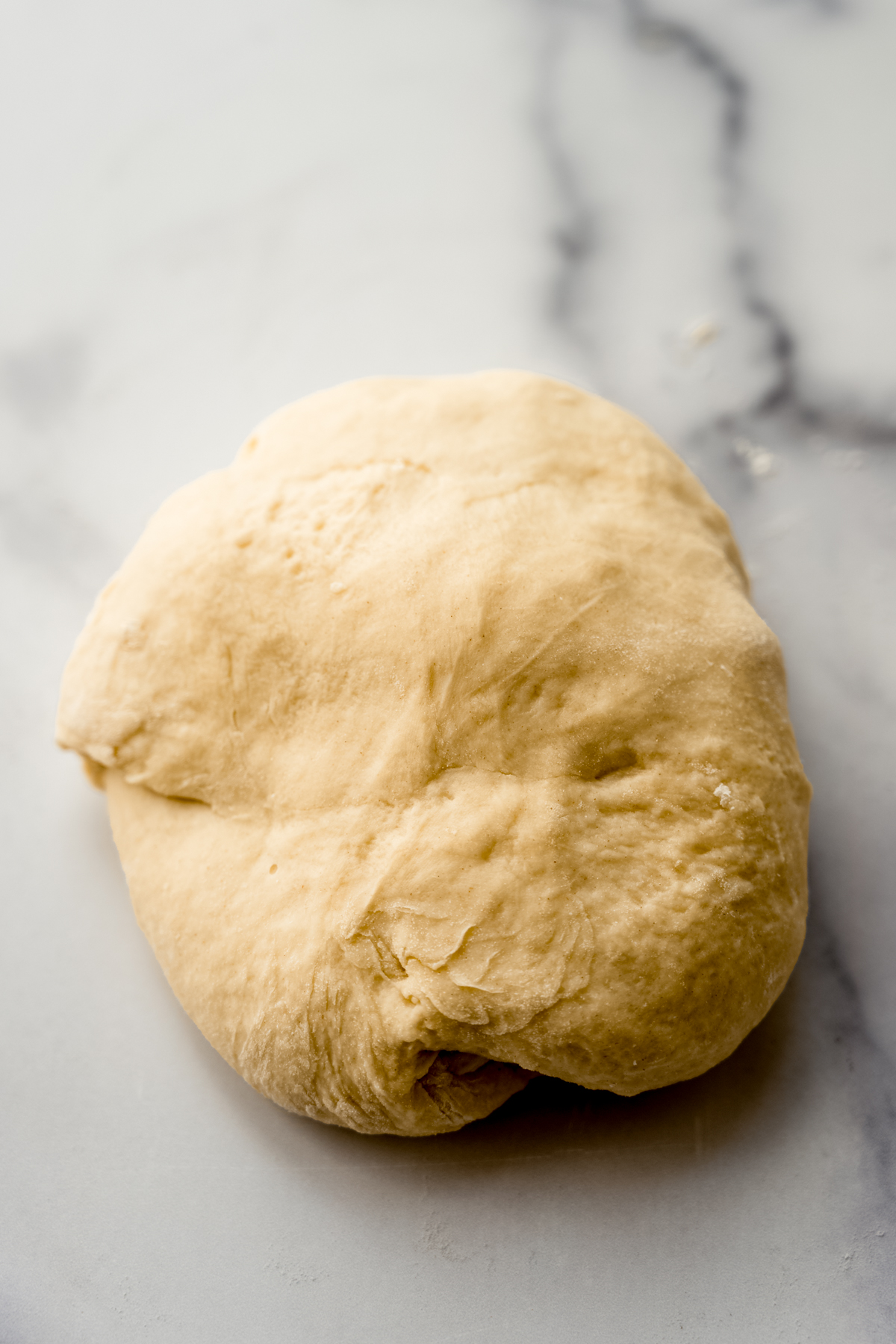 A ball of yeasted bread dough on a surface.