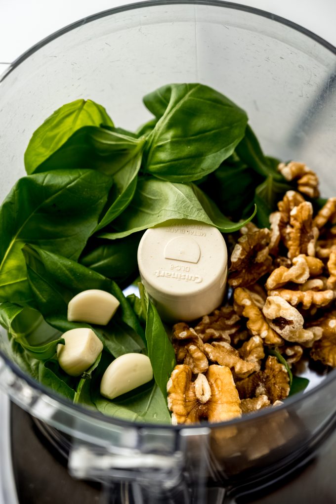 The ingredients to make pesto in the drum of a food processor.