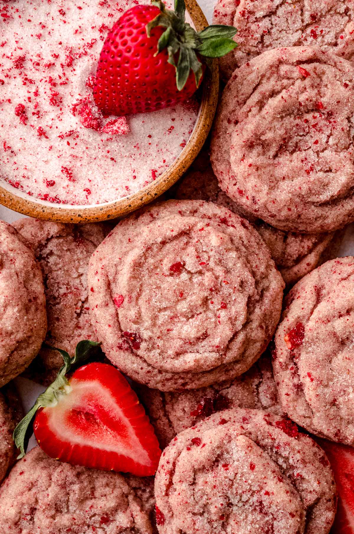 Strawberry sugar cookies on a cooling rack with fresh strawberries around them.