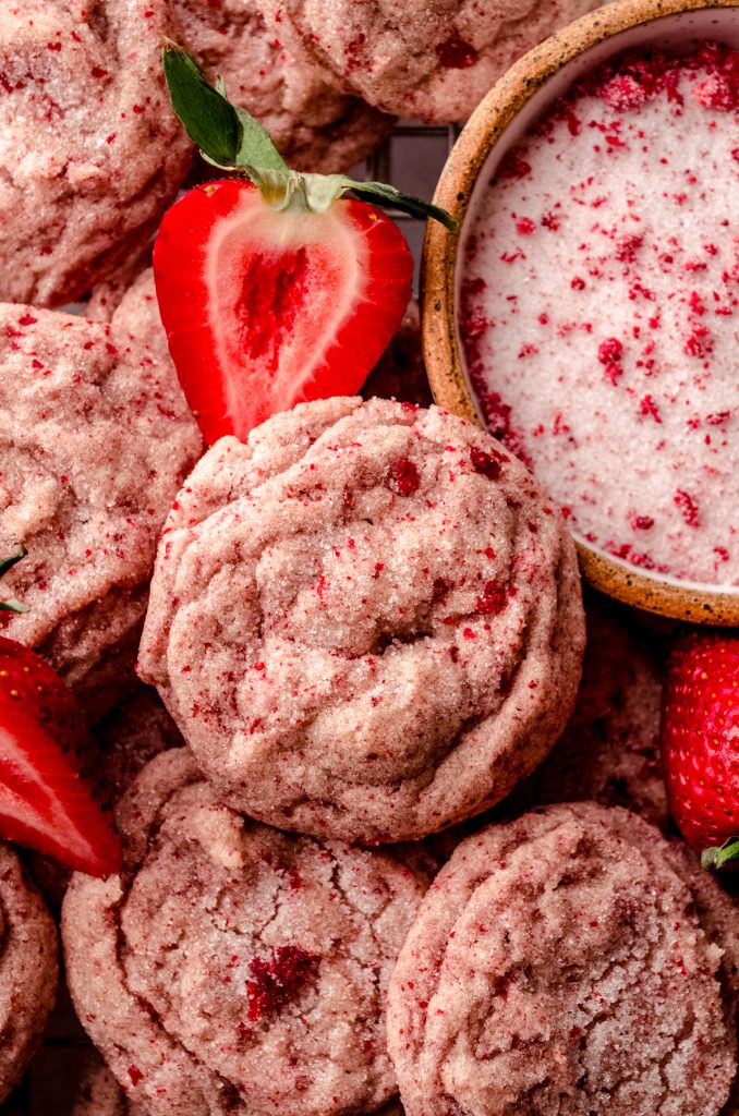 Strawberry sugar cookies on a cooling rack with fresh strawberries around them.