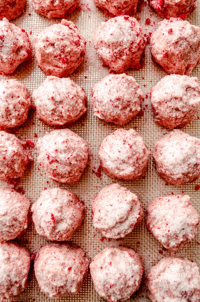 Strawberry sugar cookie dough balls on a baking sheet ready to bake.