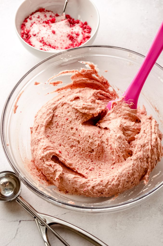 A bowl of strawberry sugar cookie dough with a spatula in it.