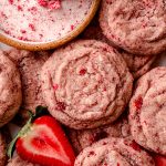 Strawberry sugar cookies on a cooling rack with fresh strawberries around them.