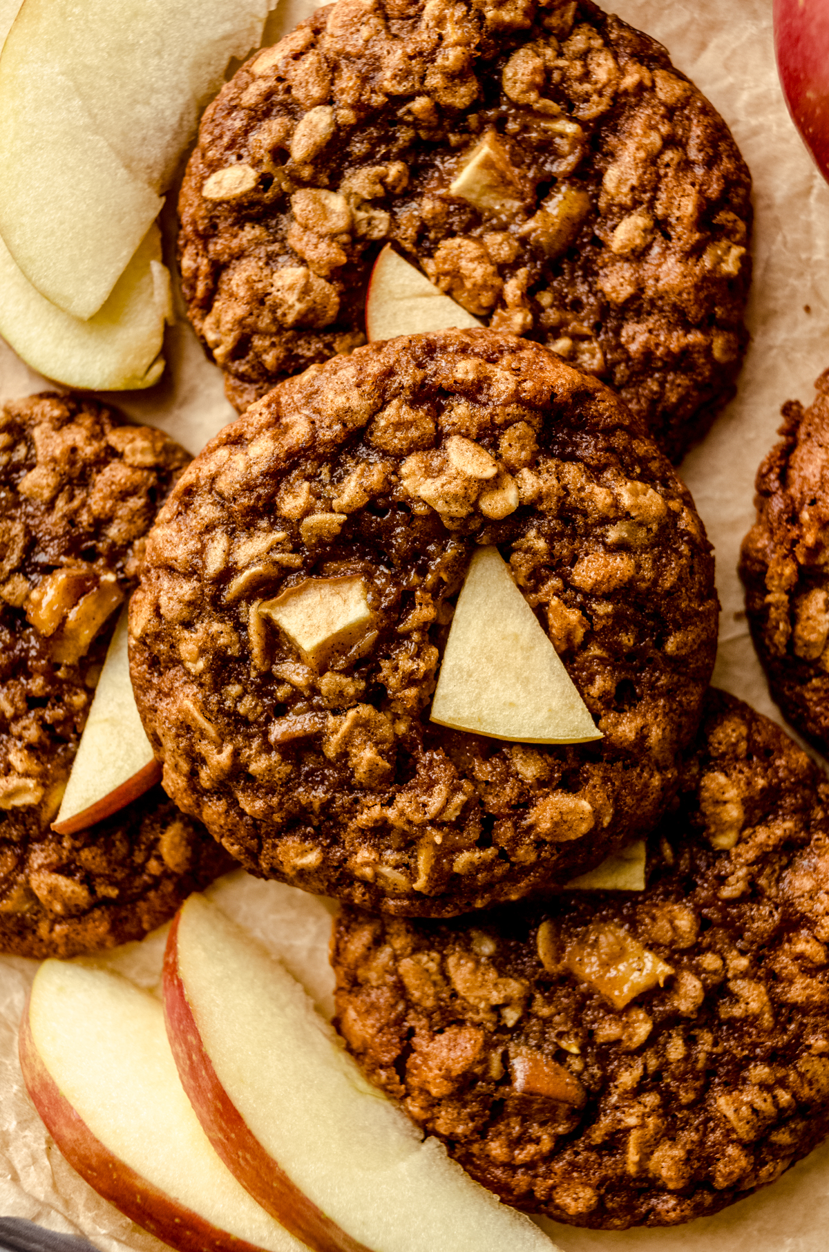 Aerial photo of apple oatmeal cookies on a surface with slices of apples around the cookies.