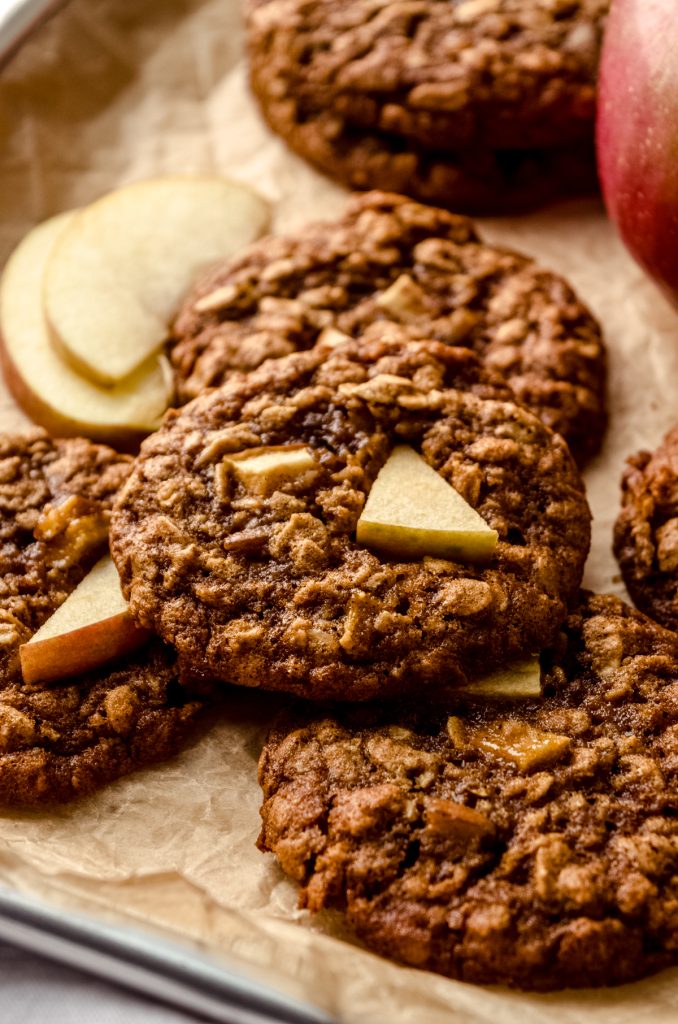 Apple oatmeal cookies on a surface with slices of apples around the cookies.