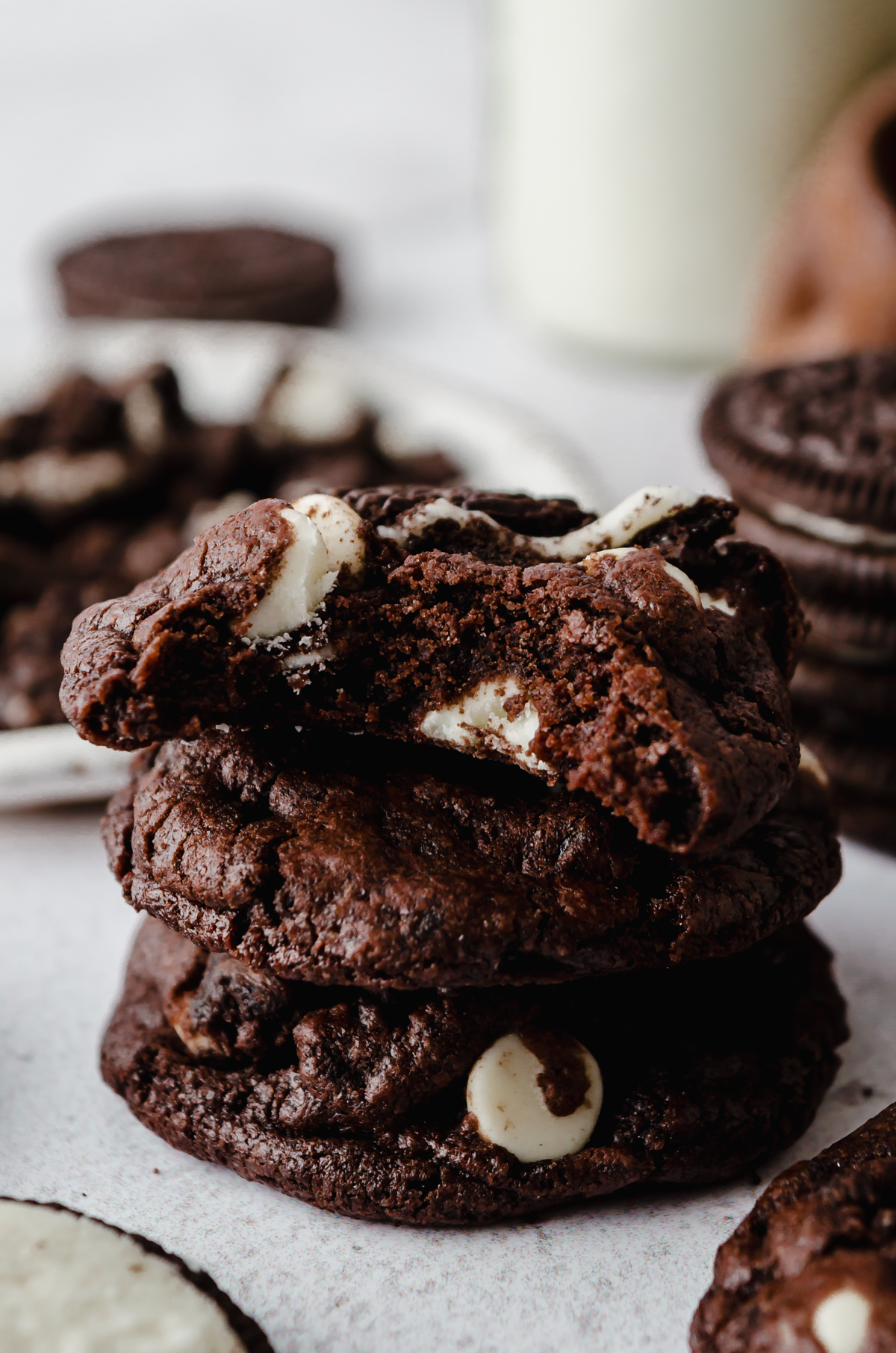 A stack of chocolate cookies and cream cookies with a bite taken out of the one on the top.