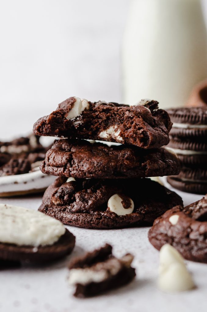 A stack of chocolate cookies and cream cookies with a bite taken out of the one on the top.