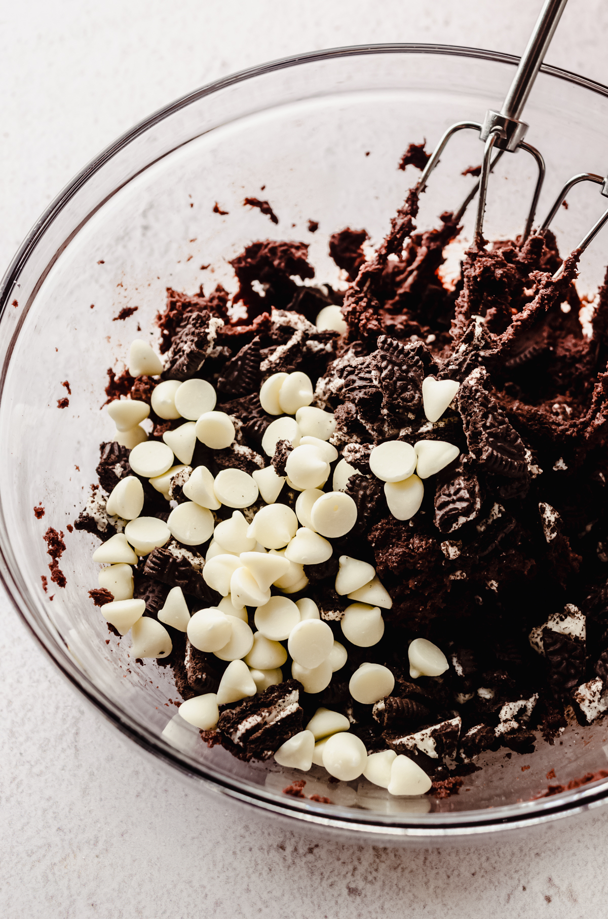 Chocolate cookies and cream cookie dough in a bowl with beaters.