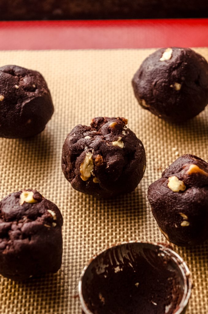 Chocolate turtle cookie dough balls on a baking sheet.