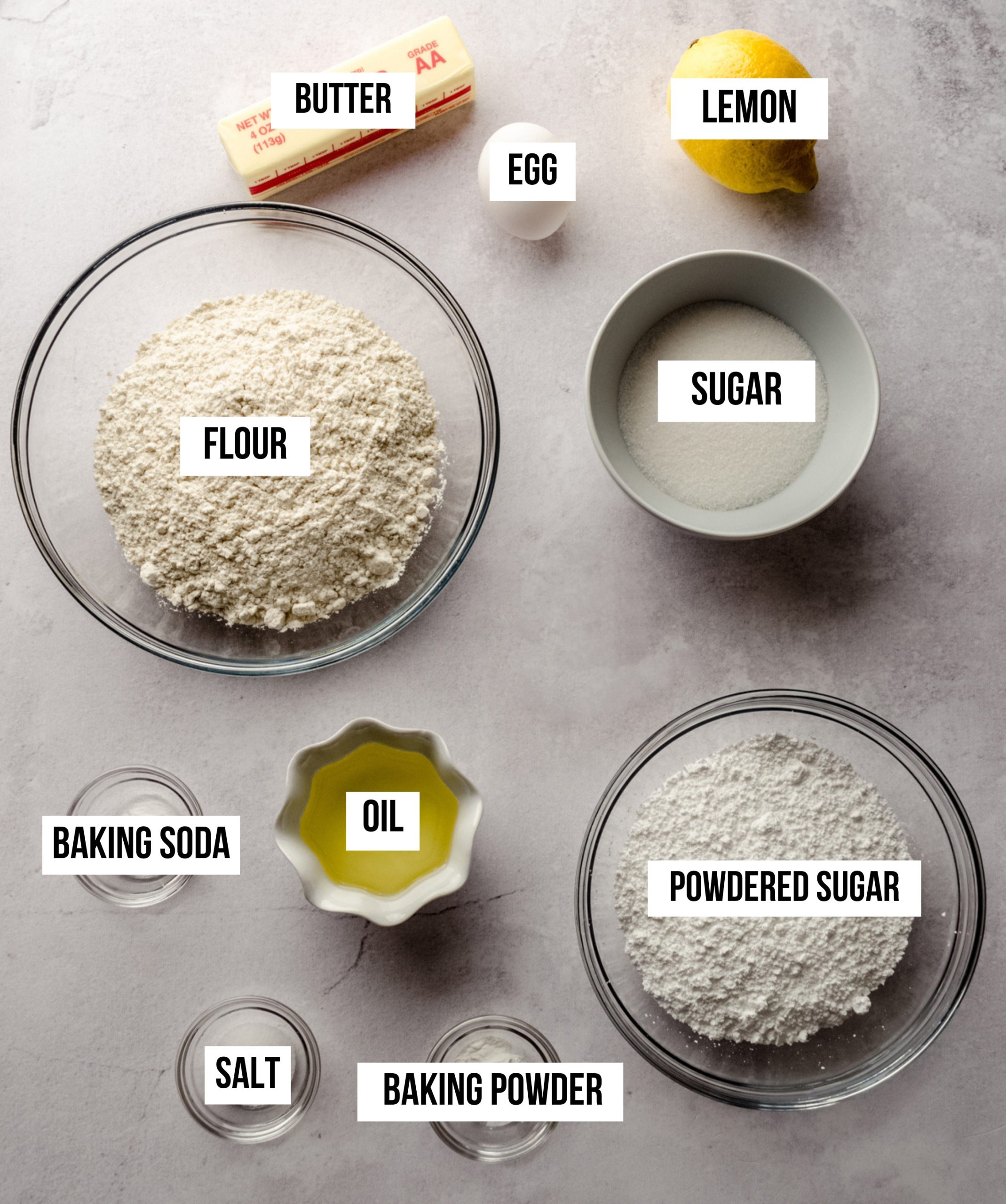 Aerial photo of the ingredients to make lemon sugar cookies with text overlay labeling each ingredient.