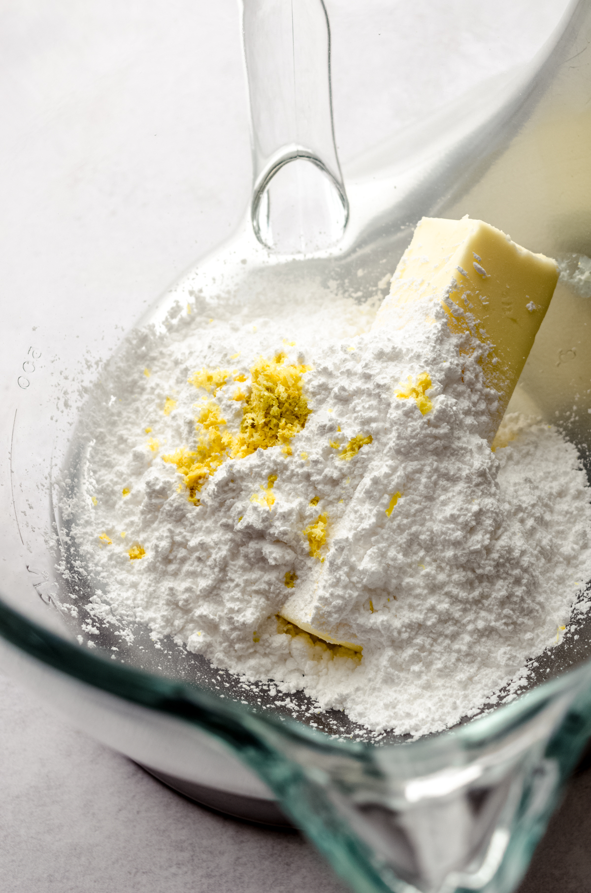 Powdered sugar, butter, and lemon zest in the bowl of a stand mixer to make lemon sugar cookies.