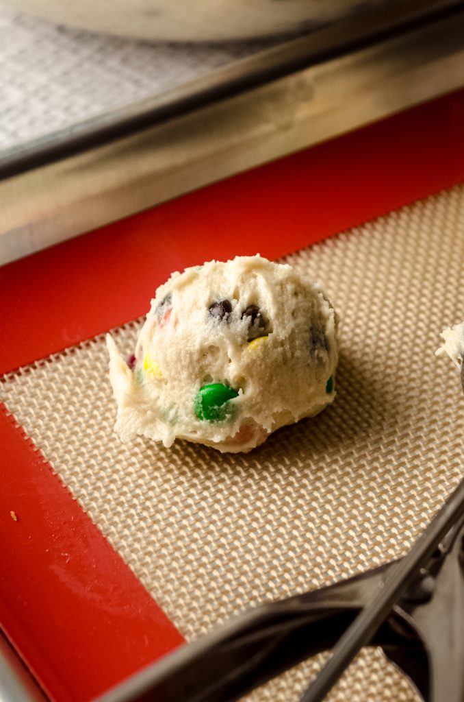 An m&m sugar cookie dough ball on a baking sheet.