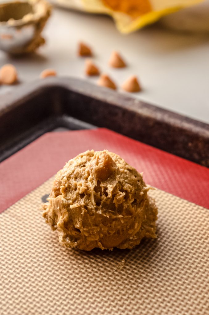 A ball of oatmeal scotchies cookie dough on a baking sheet .