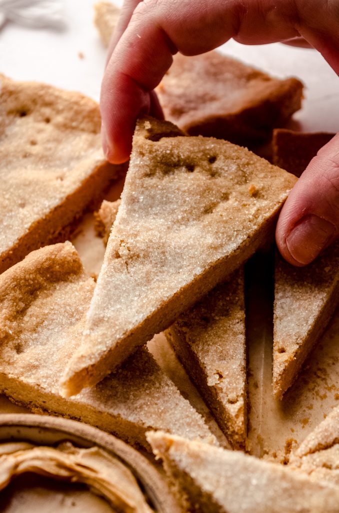 Someone is grabbing a slice of peanut butter shortbread from a stack of individual cookies.