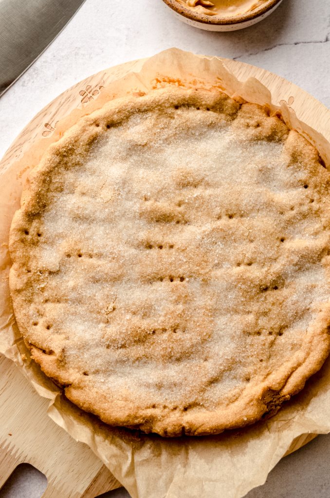 A circle of peanut butter shortbread on a piece of parchment paper.