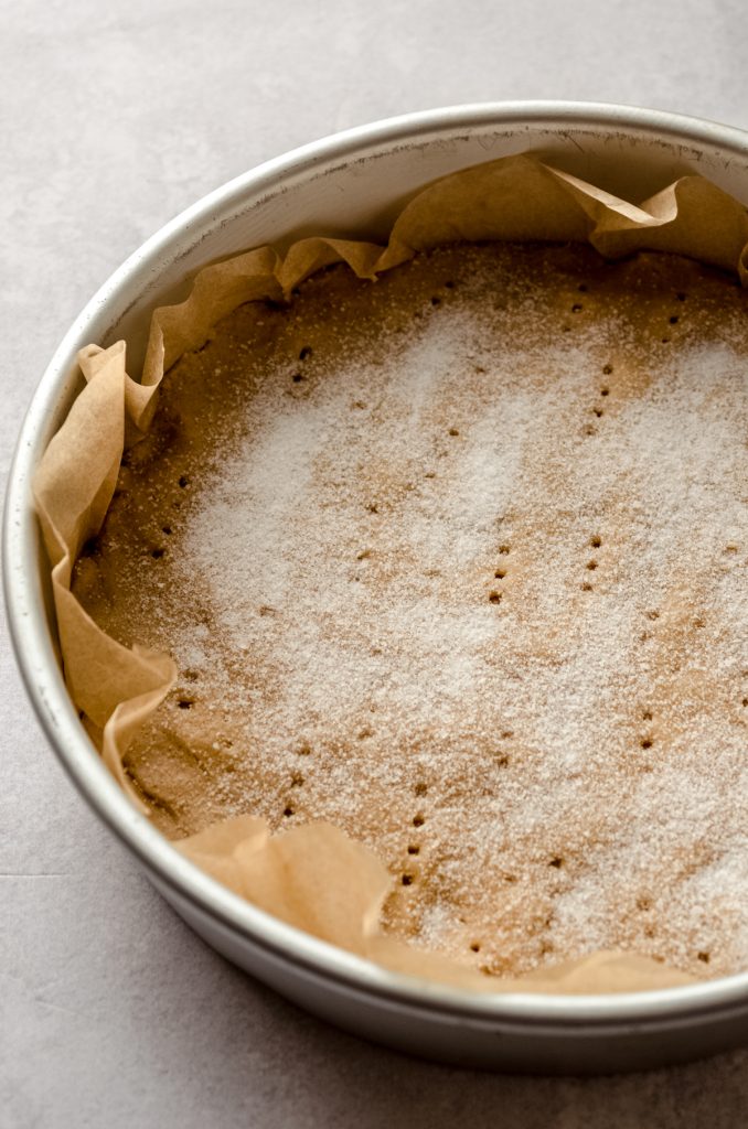 Peanut butter shortbread in a pan with fork marks and granulated sugar sprinkled on top.