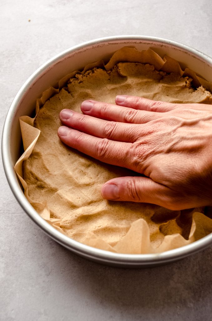 Someone is pressing peanut butter shortbread dough into a pan.